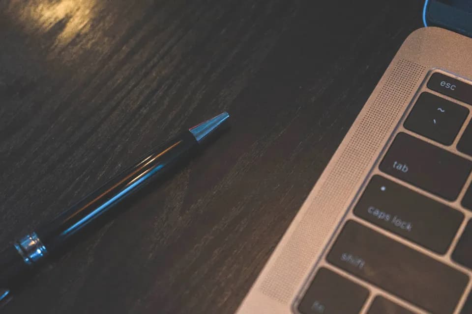 Laptop keyboard and pen on a desk ready for WordPress maintenance